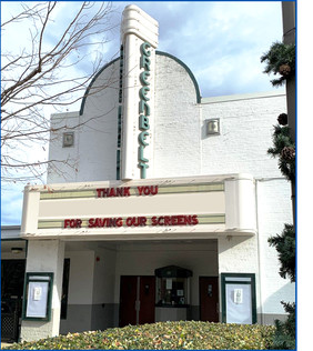 The outside view of the Old Greenbelt Theatre, brick building painted white with verticle marquee.