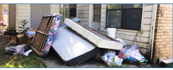 Mattresses and other junk strewn across patio in back of house are an open storage violation