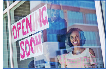 Photo of business owners hanging Opening Soon sign in front window