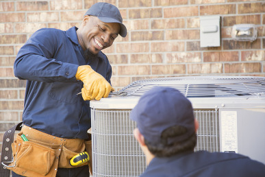 HVAC Repairman with colleague fixing air conditioning unit