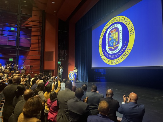County Executive Braveboy on stage at Prince George's Community College with crowd standing and clapping