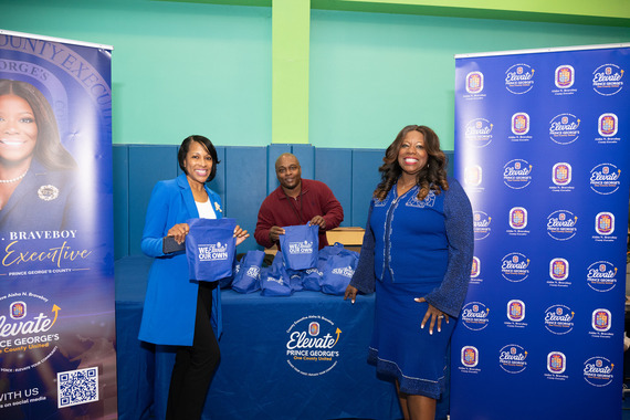 County Executive standing with Deputy Chief of Staff and Special Assistant at bold blue elevate prince george's county booth with bags