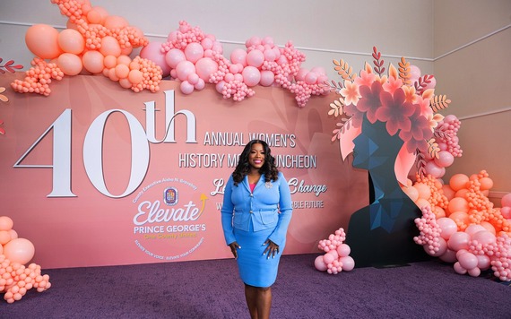 County Executive Braveboy standing in front of pink Women's History Month Luncheon WHML backdrop