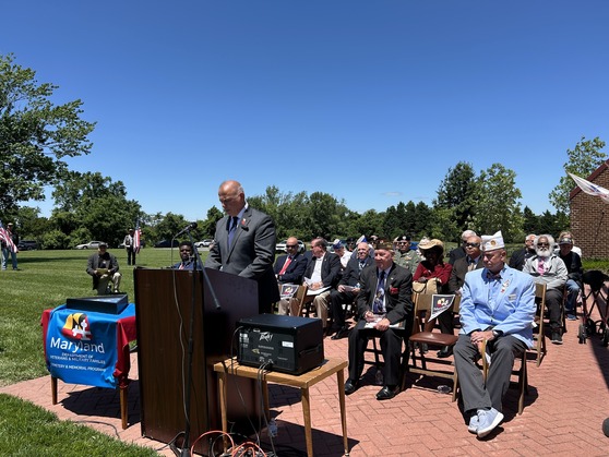 man at the podium speaking with a crowd sitting in chair at a ceremony