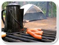 coffe and hotdogs on the grill with tent in background