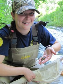 Environmental Steward with DEP holds up a small fish