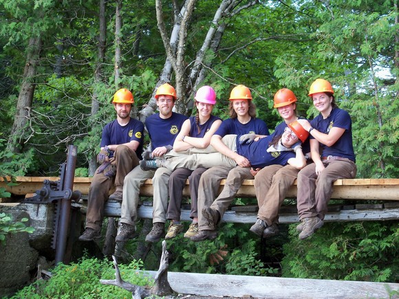 Team sitting on the edge of a bridge, one team member laying across their laps