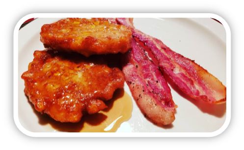 Corn fritters on plate with two slices of bacon.