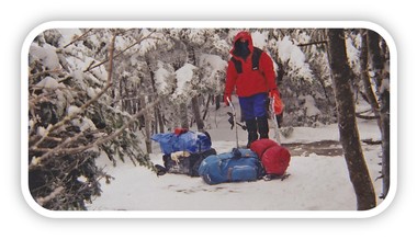 Winter camping photo showing hiker with gear ready to set-up camp.
