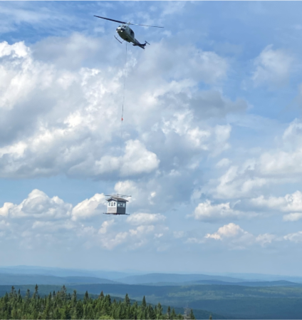 Fire tower cab being delivered to Deboullie Mt. by helicopter.