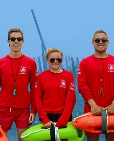 Three lifeguards with lifesaving equipment.
