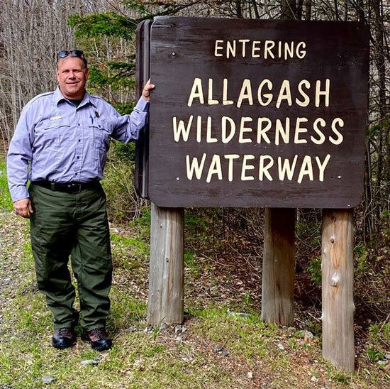 Mark Deroche, Superintendent of the Allagash Wilderness Waterway (AWW), standing next to Entering AWW sign.