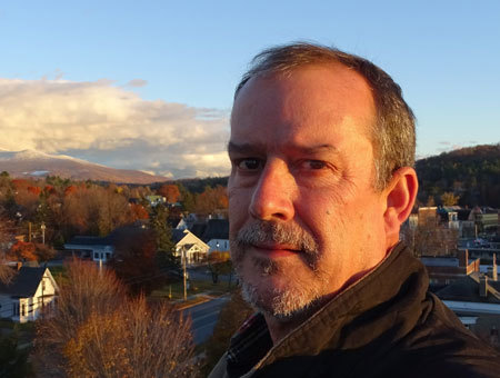 Allan Ryder, President of Timber Resource Group, with town and autumn colors on hills in background.