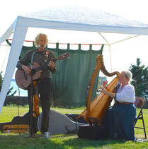 Castlebay giving an outdoor musical performance of harp and guitar.