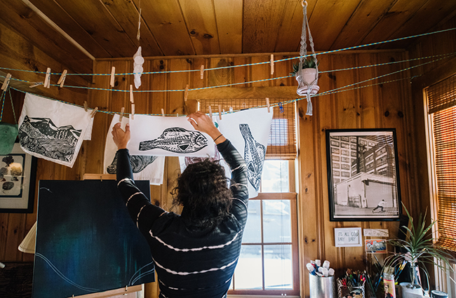 Jordan Parks, 2022 Allagash Wilderness Waterway Visiting Artist, hanging a print in her studio. Photo by Lauryn Hottinger.