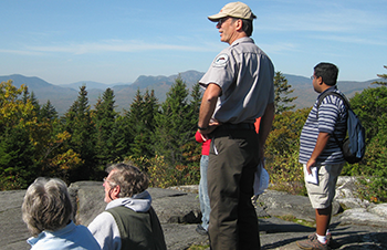 Bruce Farnham, Mount Blue State Park Manager, leading an on-trail program with a mountain view.