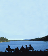 Park visitors silhouetted against a lake. 