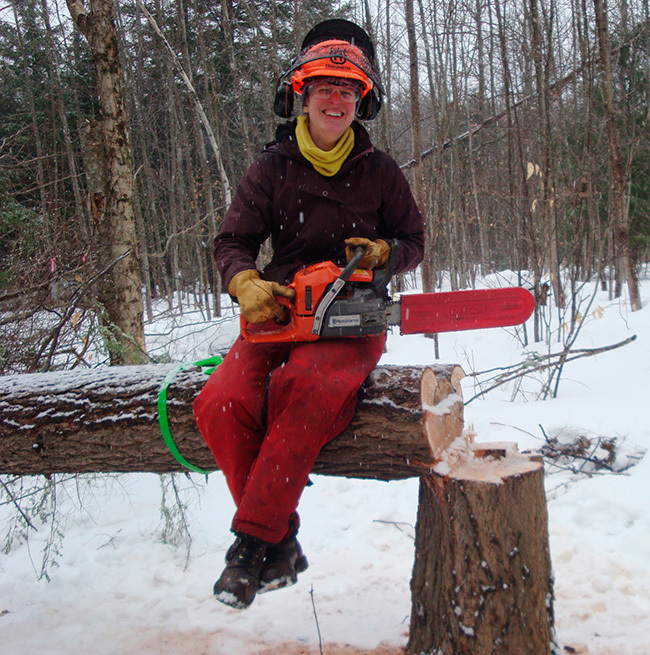 Lindsey May, MCC Field Team Program Manager, in her tree felling gear and holding a chainsaw.