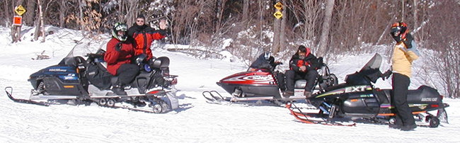 Snowmobile riders taking a break on a trail near Moosehead Lake.