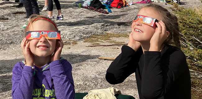 Children wearing solar glasses to enjoy the 10/14/2023 partial eclipse from the top of Bradbury Mt.