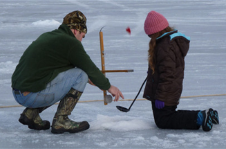 Adult and child ice fishing.