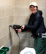 Abby Andreasen working with a drill in an outhouse at Popham Beach State Park.