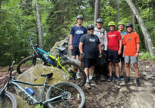 A group of bikers, ages 17 to 70, near the intersection of Runaway Train and Bootlegger trails at Moosehead Junction Trails.