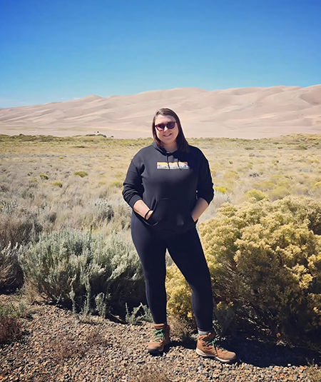 Photo of staff member Jessica Sayers in the desert southwest with sand hills in the distance.