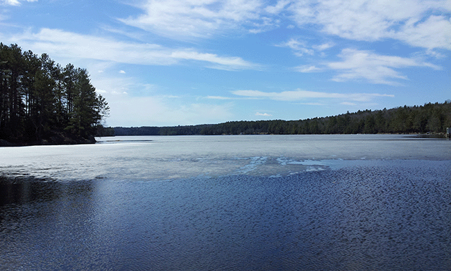 A lake with ice receding from the shore.