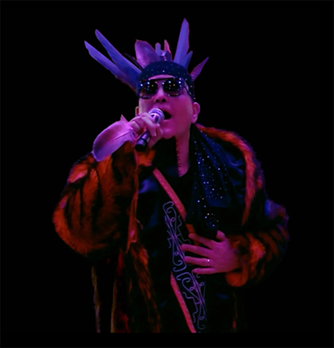 Performer Firefly the Hybrid singing and wearing Penobscot regalia.