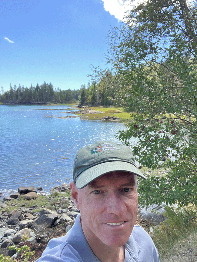 Maine Bureau of Parks and Lands Director Andy Cutko at Cobscook Bay State Park with the rocky shoreline behind him.