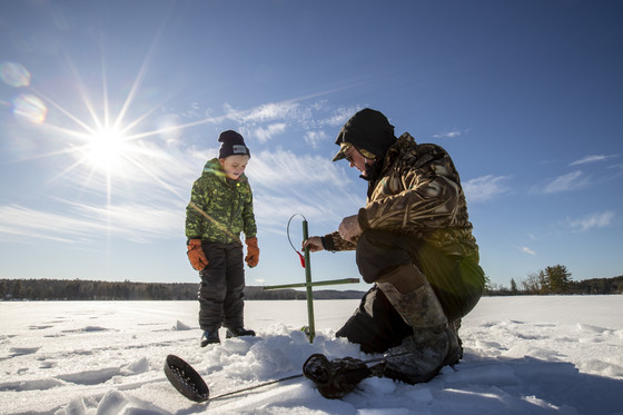 grandson and grandfather ice fishing on sunny day