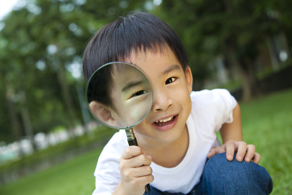 child looking through magnifying glass