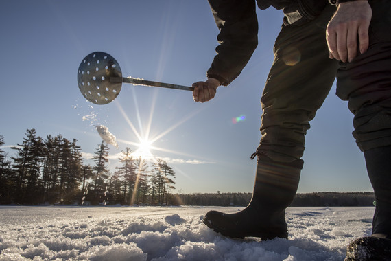 skimming ice fishing hole with sun burst in back