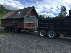 log cabin on bed of haul truck