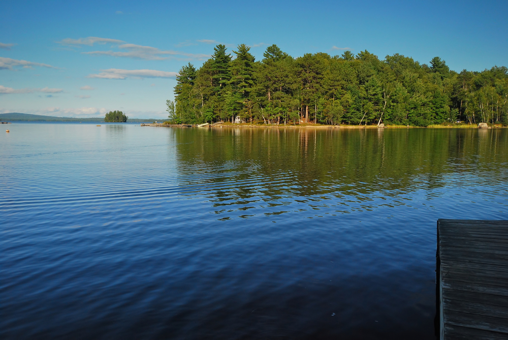  Maine lake with clear blue sky and pine trees in background