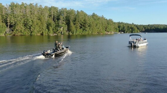 warden service bass boat approaching a pontoon boat in the middle of a lake