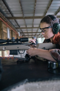 woman loading a rifle to target practice at a range