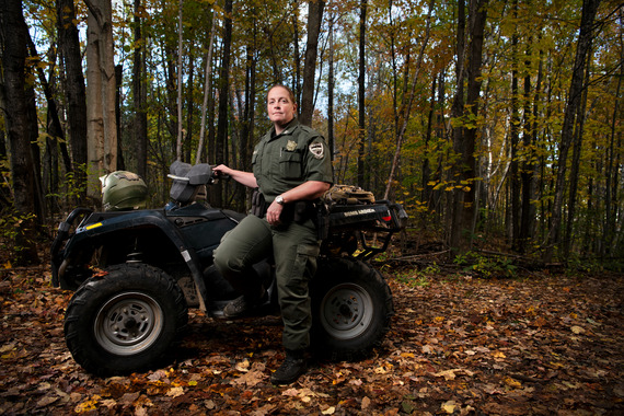 Maine game warden next to an ATV with fall foliage