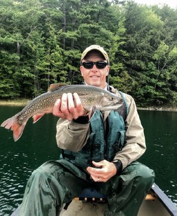 fisheries biologist in a canoe holding a large brook trout