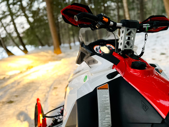 red and white snowmobile parked on side of trail