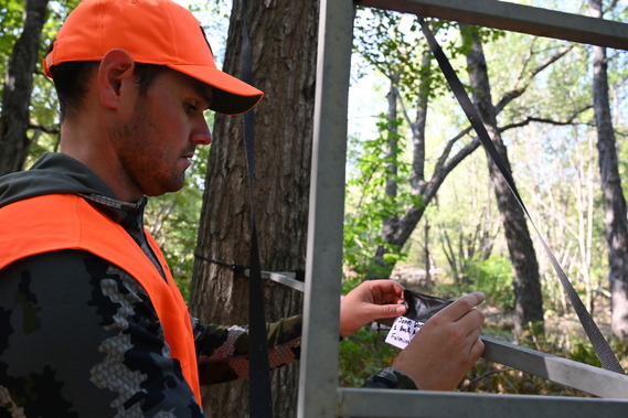 hunter adding contact information to treestand in the woods