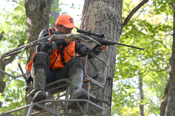 Hunter with rifle in tree stand