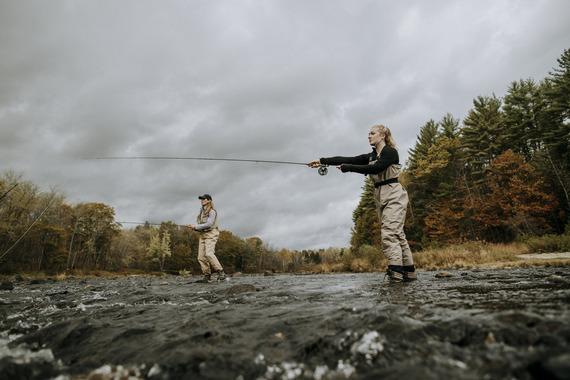 two fly anglers on a river with slight fall foliage background