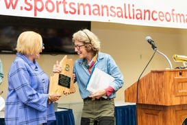 Alexandra receives Maine shaped wooden award from Governor Janet Mills with big smiles