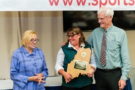 Tenley excitedly holds State of Maine shaped wooden award next to Governor Janet Mills and MDIFW Deputy Commissioner Tim Peabody