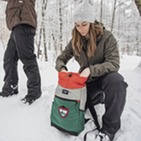 A person packing a backpack outside in winter