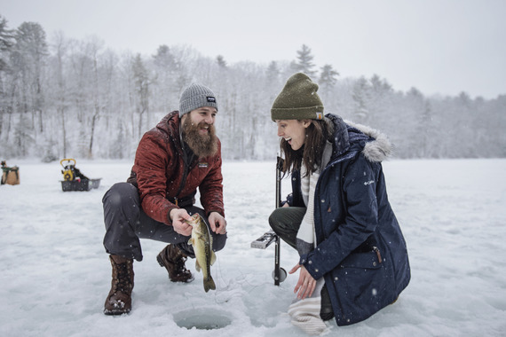 woman and man ice fishing and catching a largemouth bass