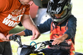 A camp north woods instructor teaching a child how to operate an ATV