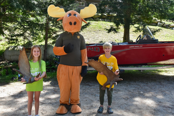 two kids holding moose antlers next to a moose mascot